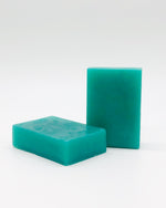 Two semi-transparent rectangular teal soap bars on a white background.