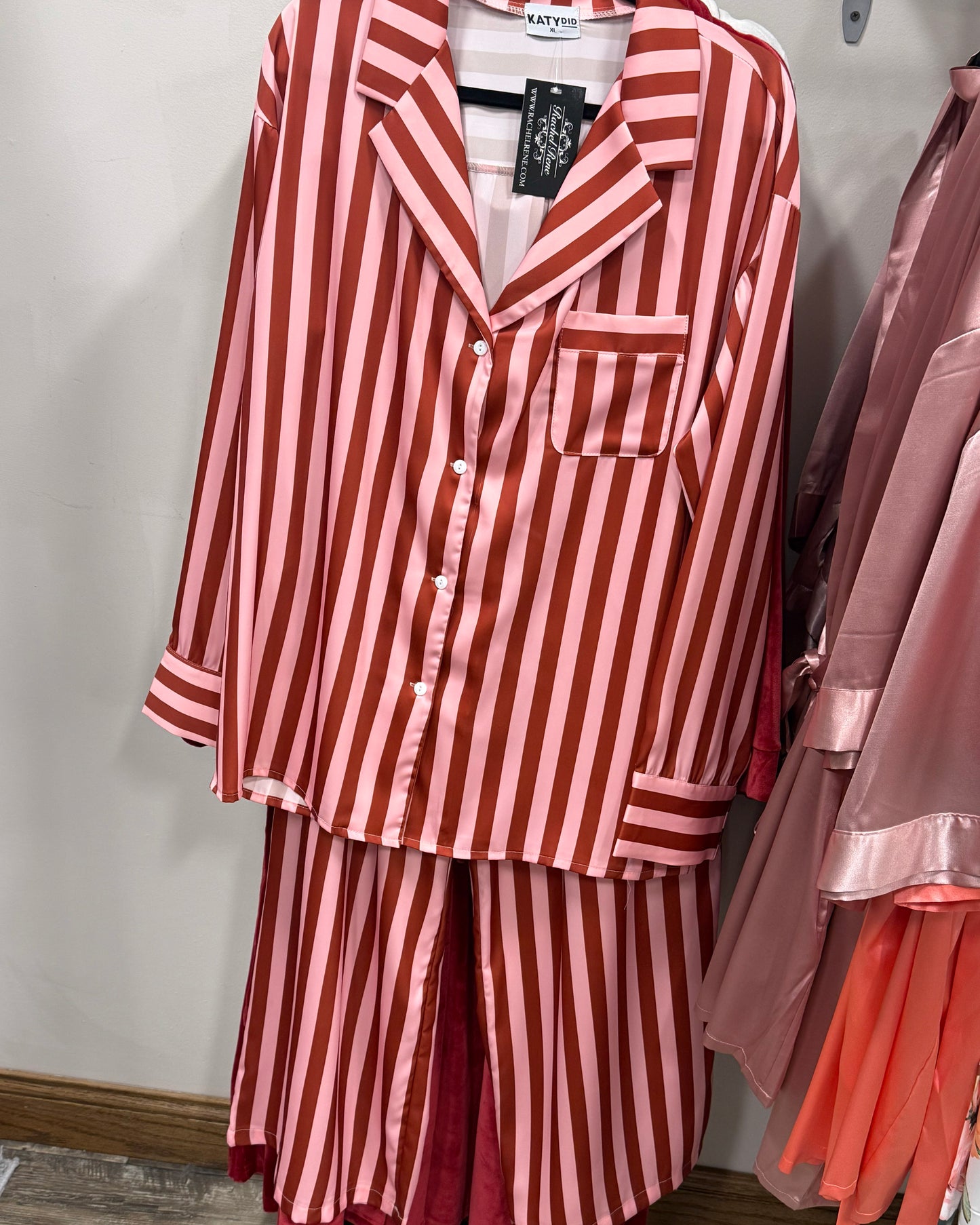 Red and pinkstriped pajama set on a hanger against a neutral background