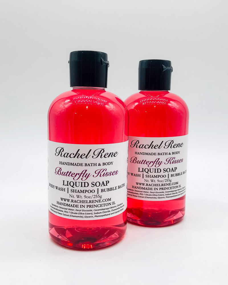 Two semi-transparent pink liquid soaps with a white label that reads "Rachel Rene: Handmade Bath & Body - Butterfly Kisses. Liquid Soap - Body Wash - Shampoo - Bubble Bath." They have black pull top caps and sit on a white background.