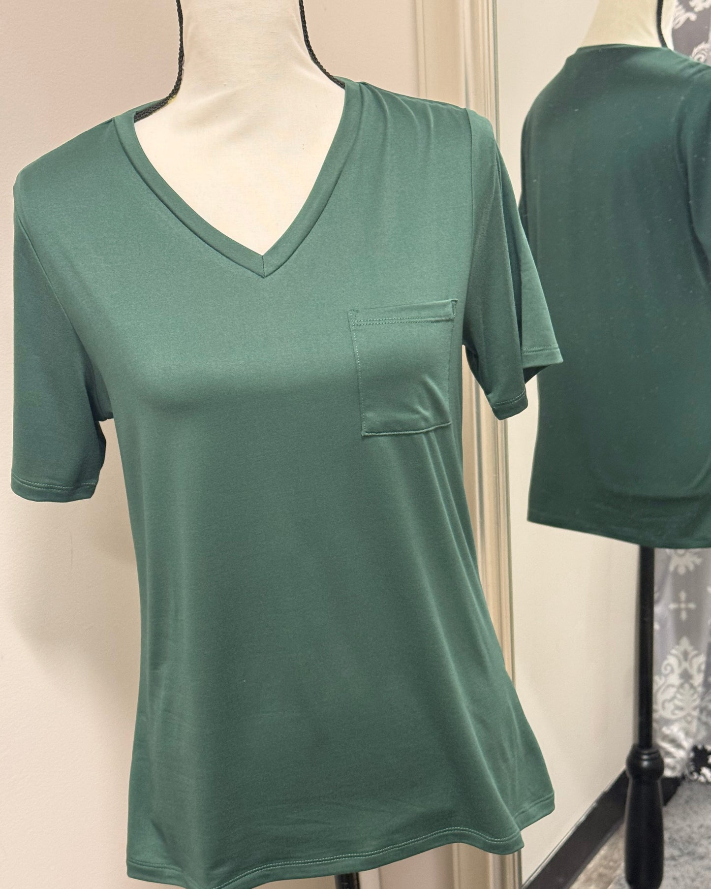 Green t-shirt with a pocket on a mannequin against a neutral background