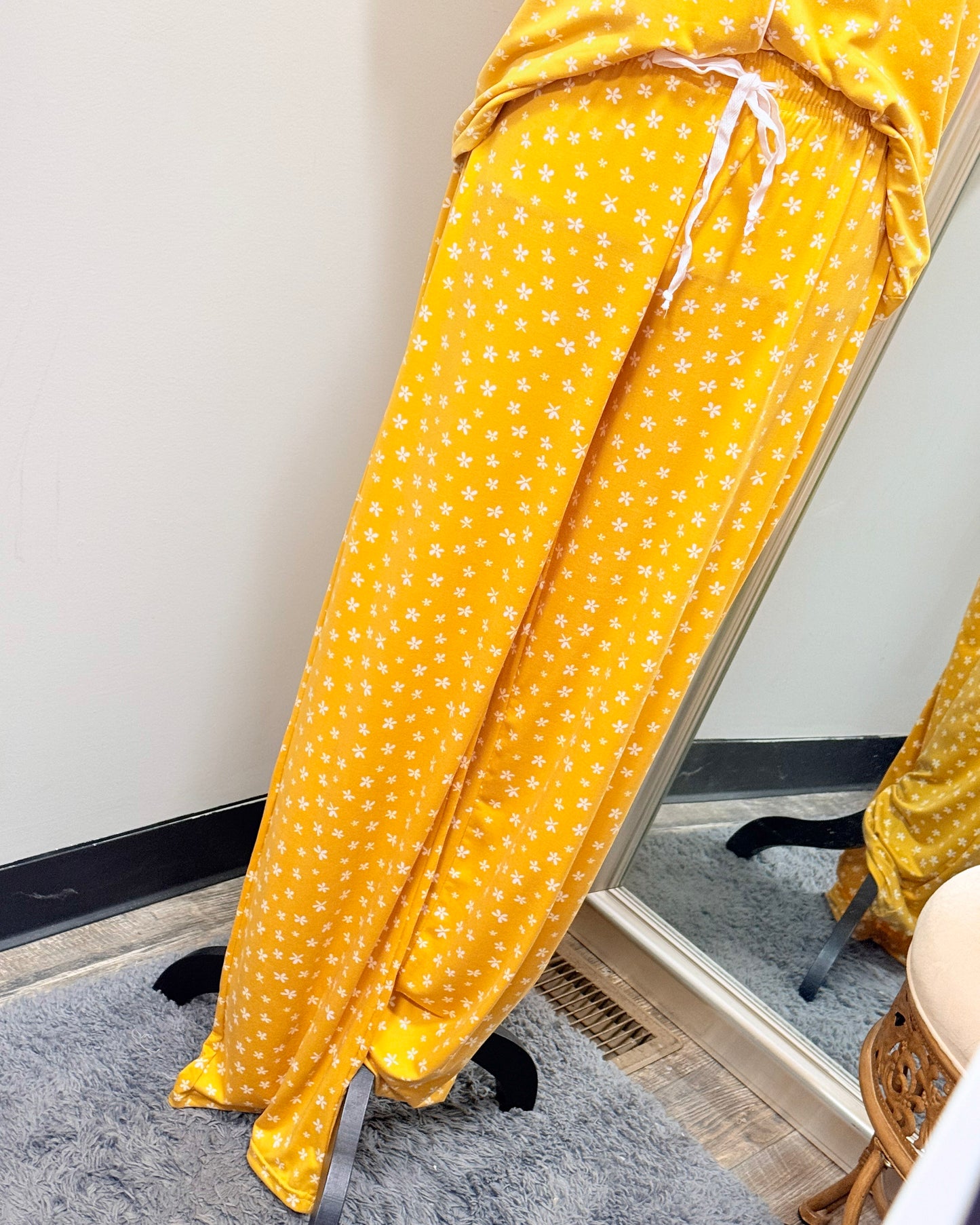 Yellow pajama pants with white flower pattern on a mannequin against a neutral background