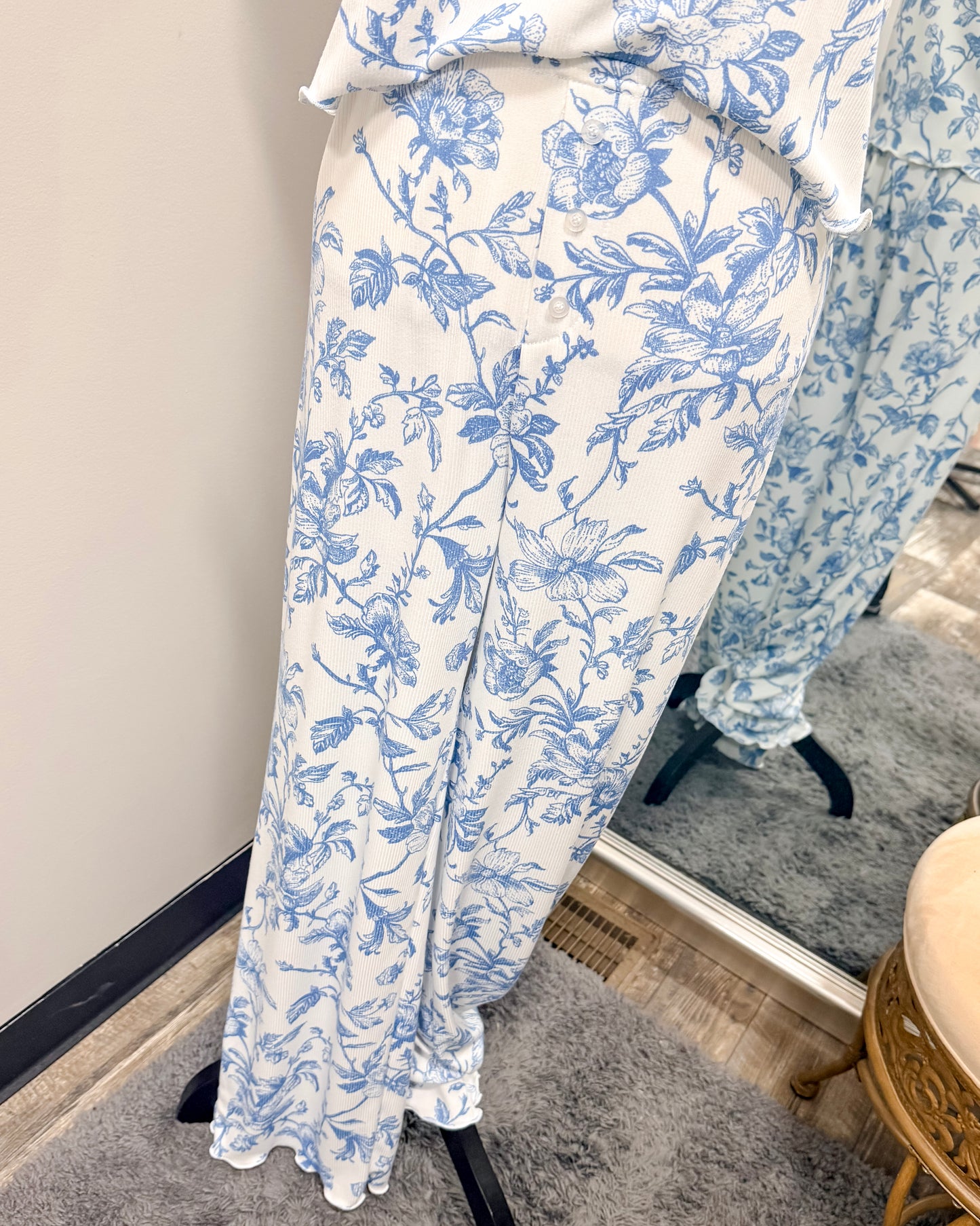 Blue floral pajama pants on a stand against a neutral wall.