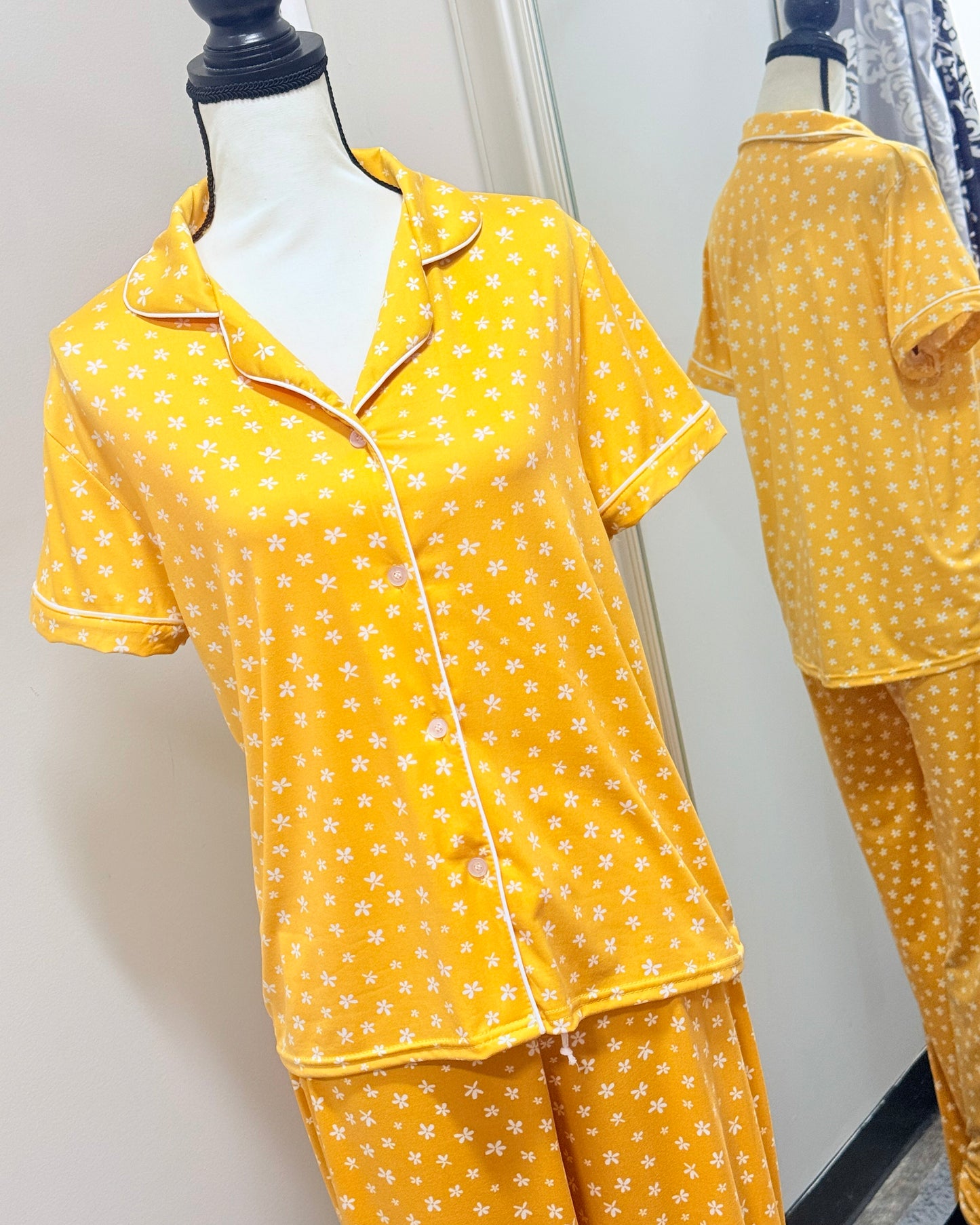 Yellow pajama set with white floral pattern on a mannequin against a plain background