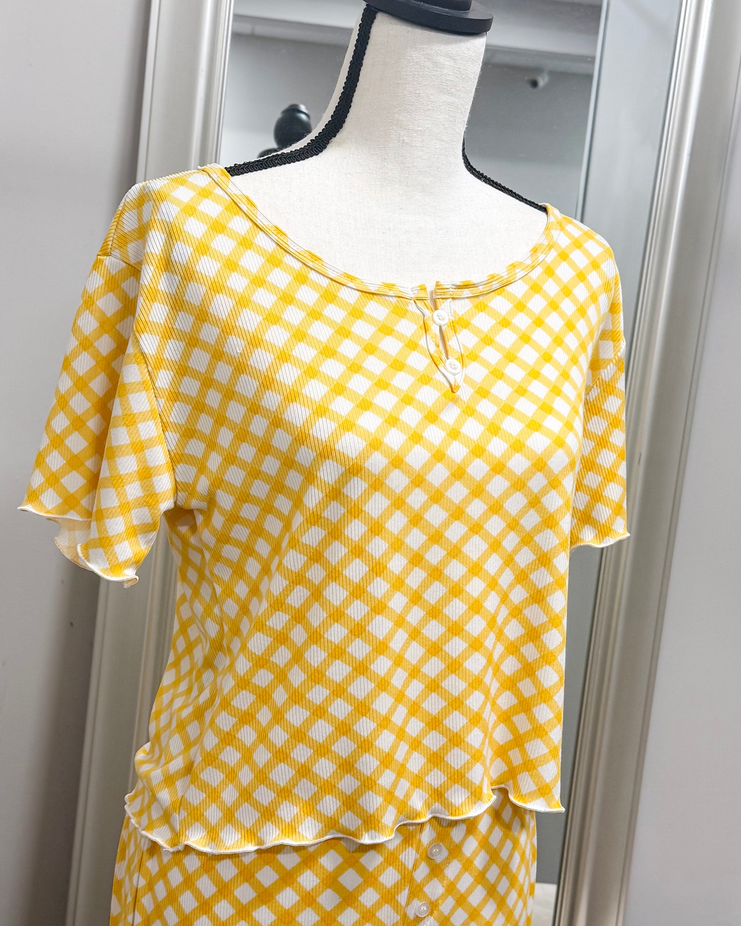 Yellow and white checkered pajama top on a mannequin against a neutral background
