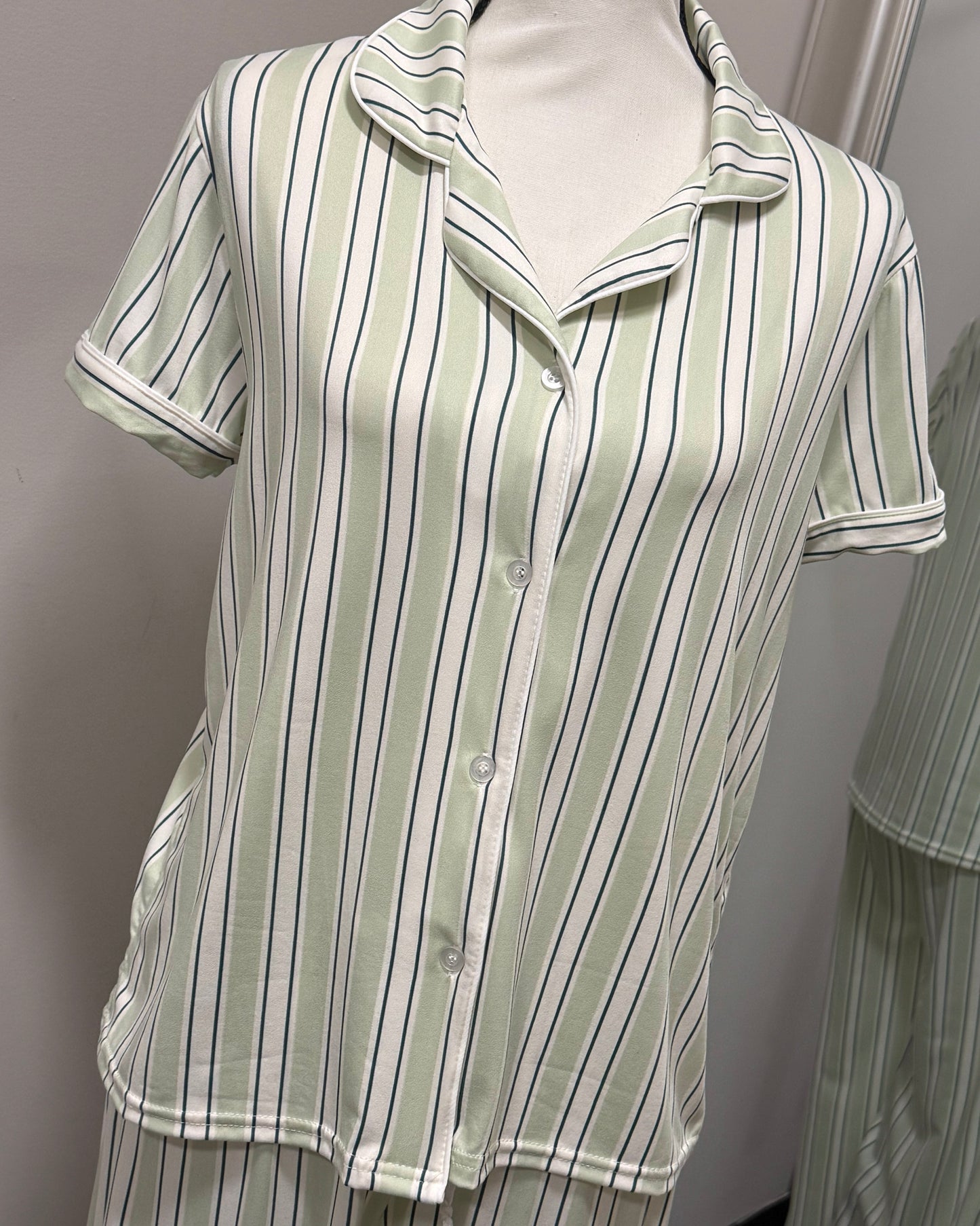 Green and white striped shirt on a mannequin against a gray background