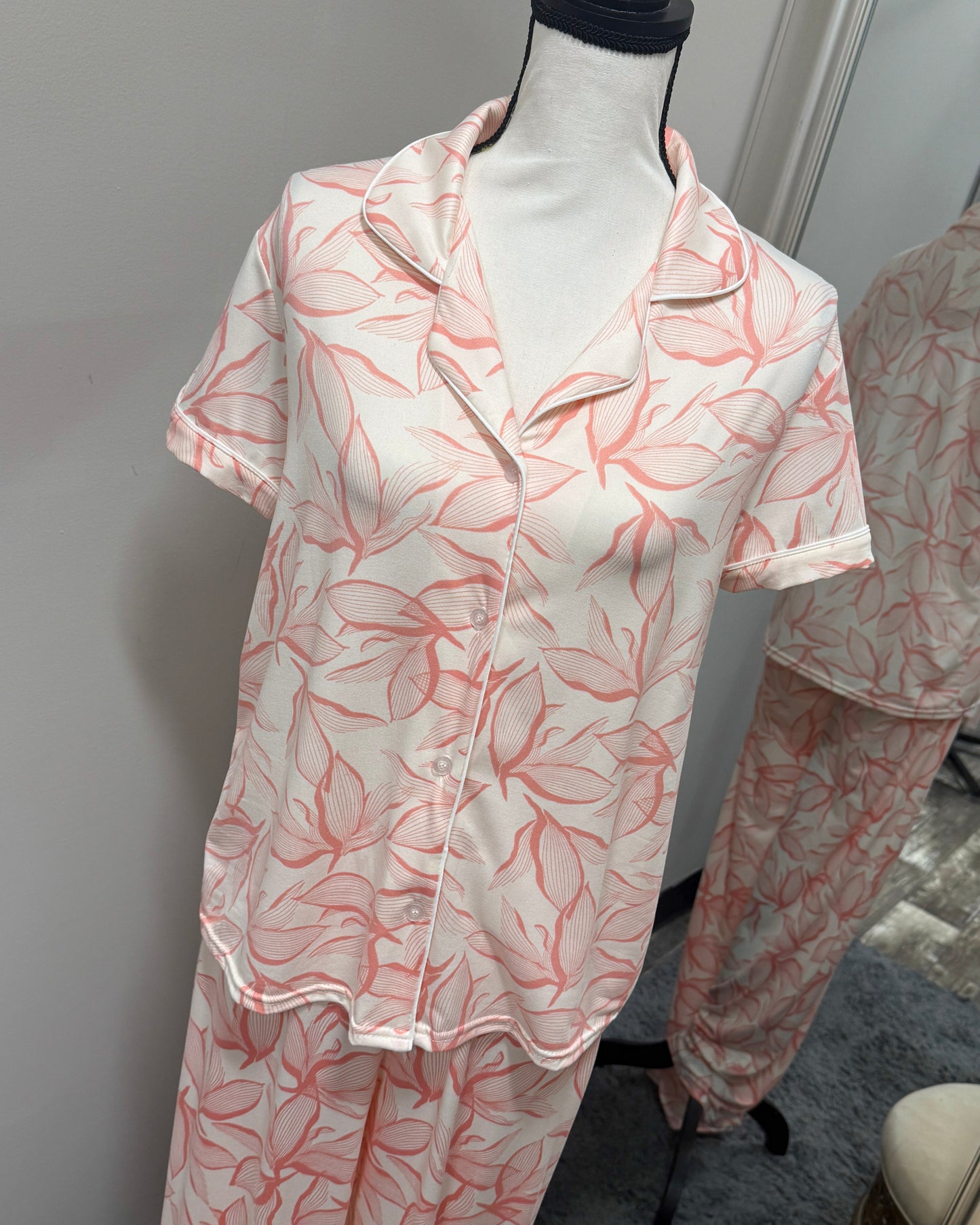 Pink floral pajama set on a mannequin against a gray wall.