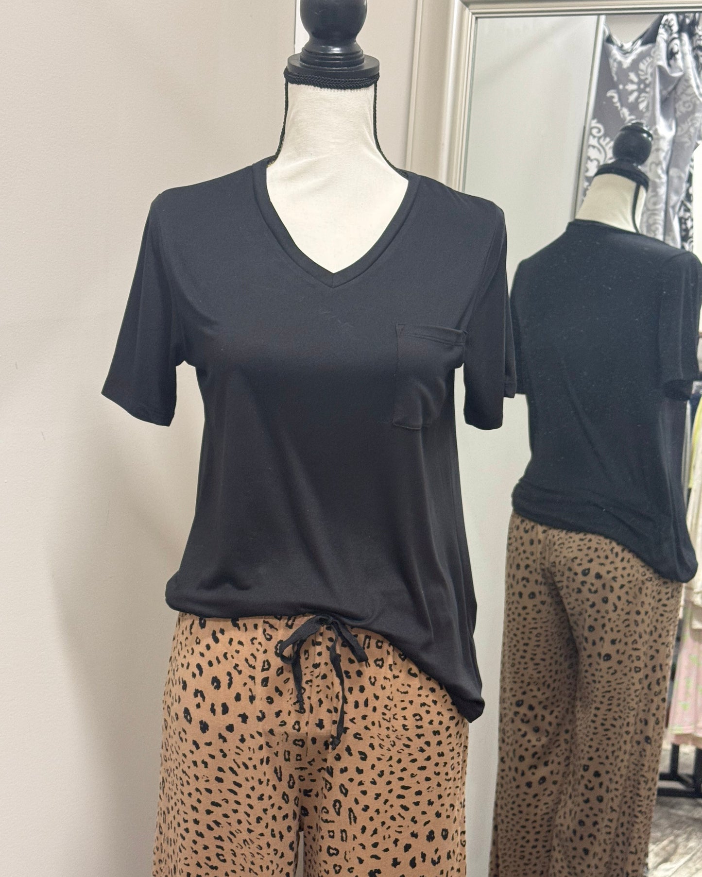 Mannequin wearing a black t-shirt with a pocket and leopard print pants against a plain background