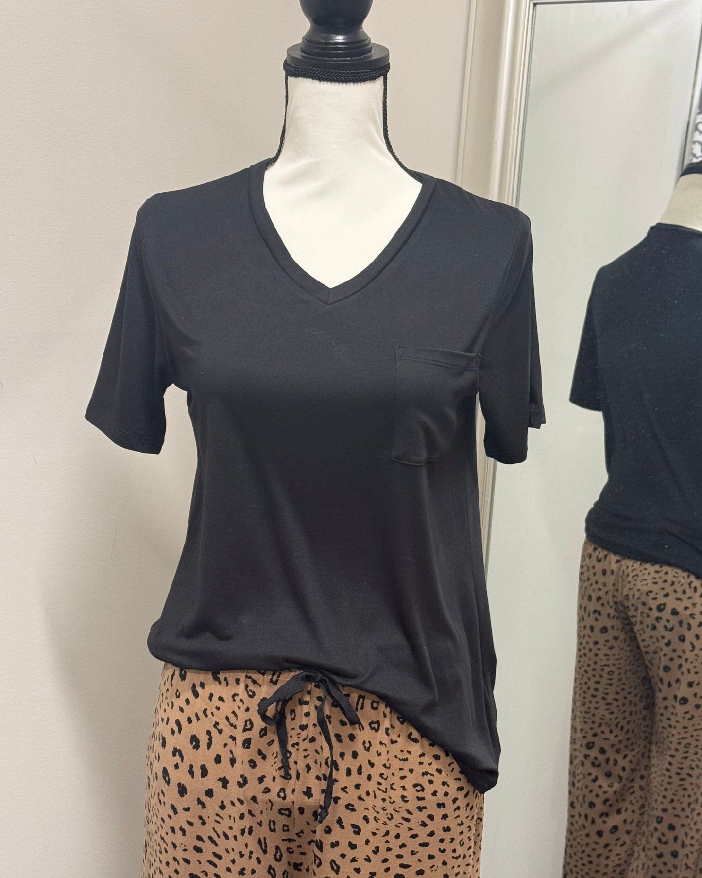 Mannequin wearing a black t-shirt with a pocket and leopard print pants against a plain background