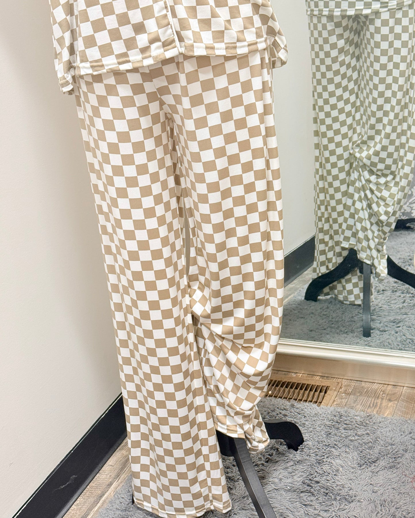 Beige and white checkered pajama pants displayed in front of a mirror.