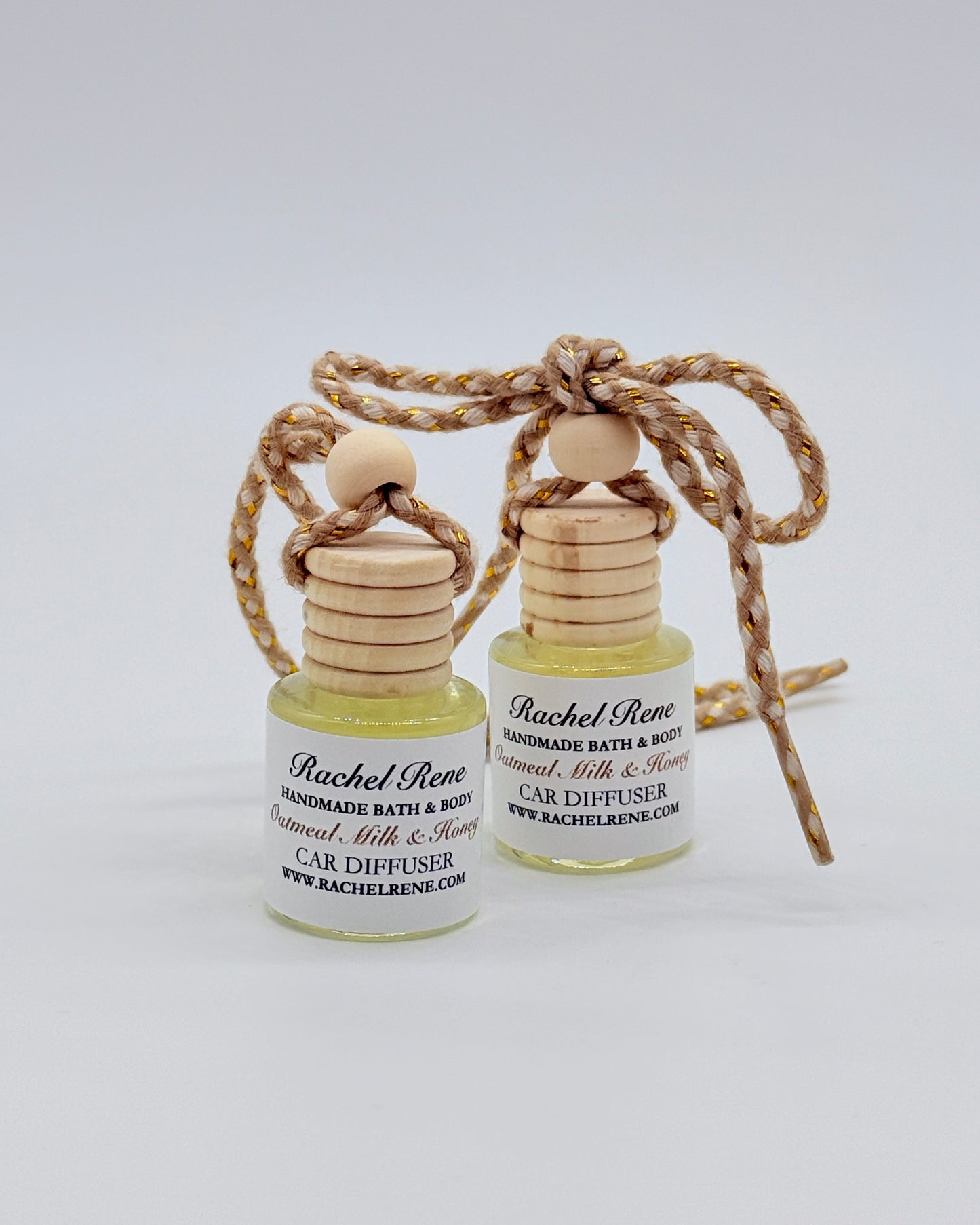 Two bottles of Rachel Rene Car Diffuser with wooden tops and braided string on a white background