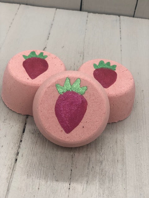 Pink strawberry scented bubble bombs with a red strawberry painted on the top with a green stem