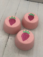 Pink strawberry scented bubble bombs with a red strawberry painted on the top with a green stem
