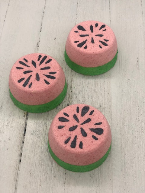 Watermelon scented bubble bombs with green on the bottom and pinkish red on the top half painted with black seeds on the very top