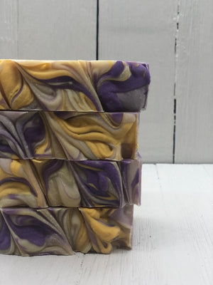 
            
                Load image into Gallery viewer, A khaki colored soap bar with purple and gold swirls.
            
        
