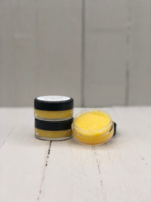 
            
                Load image into Gallery viewer, Yellow lip scrub in a small clear pot with a black lid.
            
        