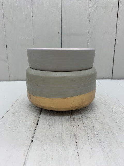
            
                Load image into Gallery viewer, A gray ceramic wax warmer with a gold band on the bottom. There is a matching cup on top of the warmer.
            
        